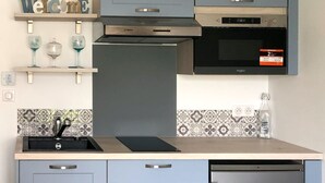 Una cucina moderna con mobili grigi, una cappa Bosch, un forno Whirlpool e una lavastoviglie.