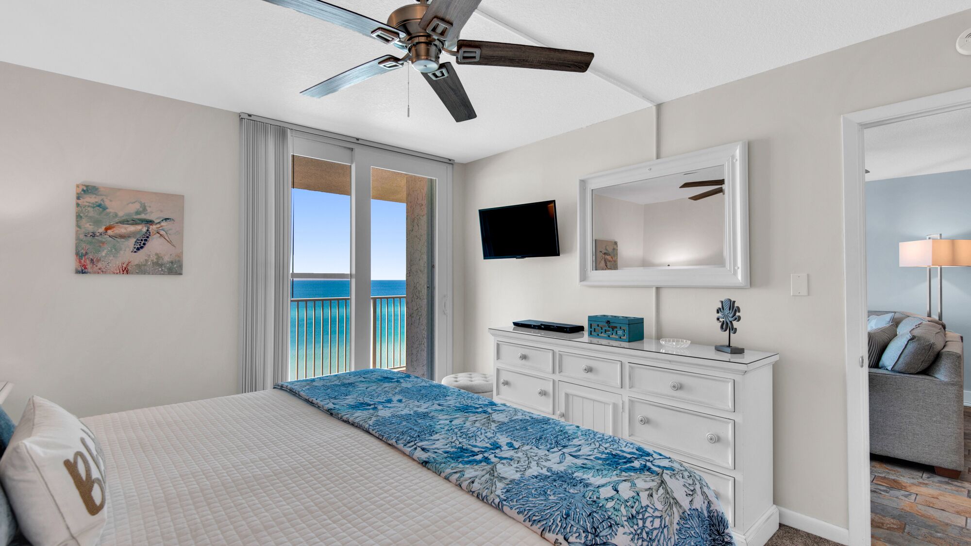 A bedroom with a bed, a dresser, a TV, and a ceiling fan.