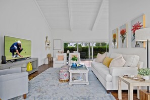 A modern living room with a television, white sofas, a coffee table, and a view of the outdoors. - LQ003 - La Quinta / Montero Estates Pet Friendly Home (La Quinta)