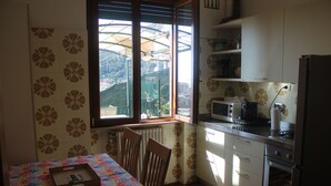 A kitchen with a dining table, chairs, a microwave, and a refrigerator. - Il Paradiso Vista Mare (Levanto)