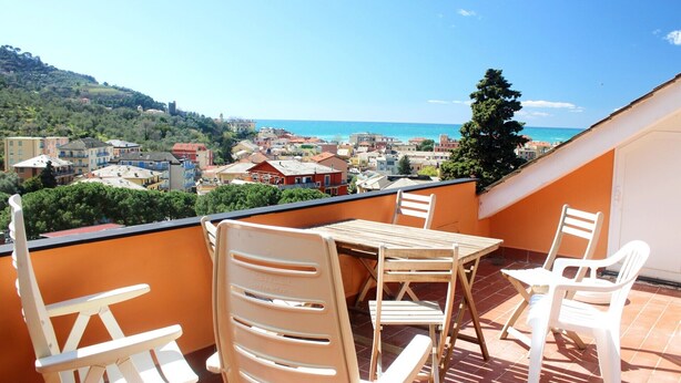 A balcony with a table and chairs overlooking a coastal town. - Il Paradiso Vista Mare (Levanto)