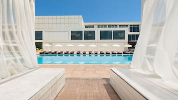 Una piscina techada, sombrillas, sillones reclinables de piscina