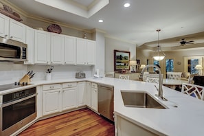 Una cocina moderna con armarios blancos, electrodomésticos de acero inoxidable y piso de madera.