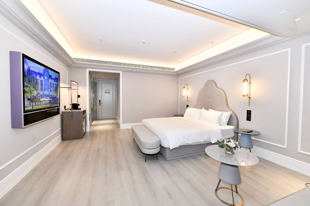 Ein modernes Hotelzimmer mit einem großen Bett, Nachttischen, einem Fernseher und einem Schreibtisch.