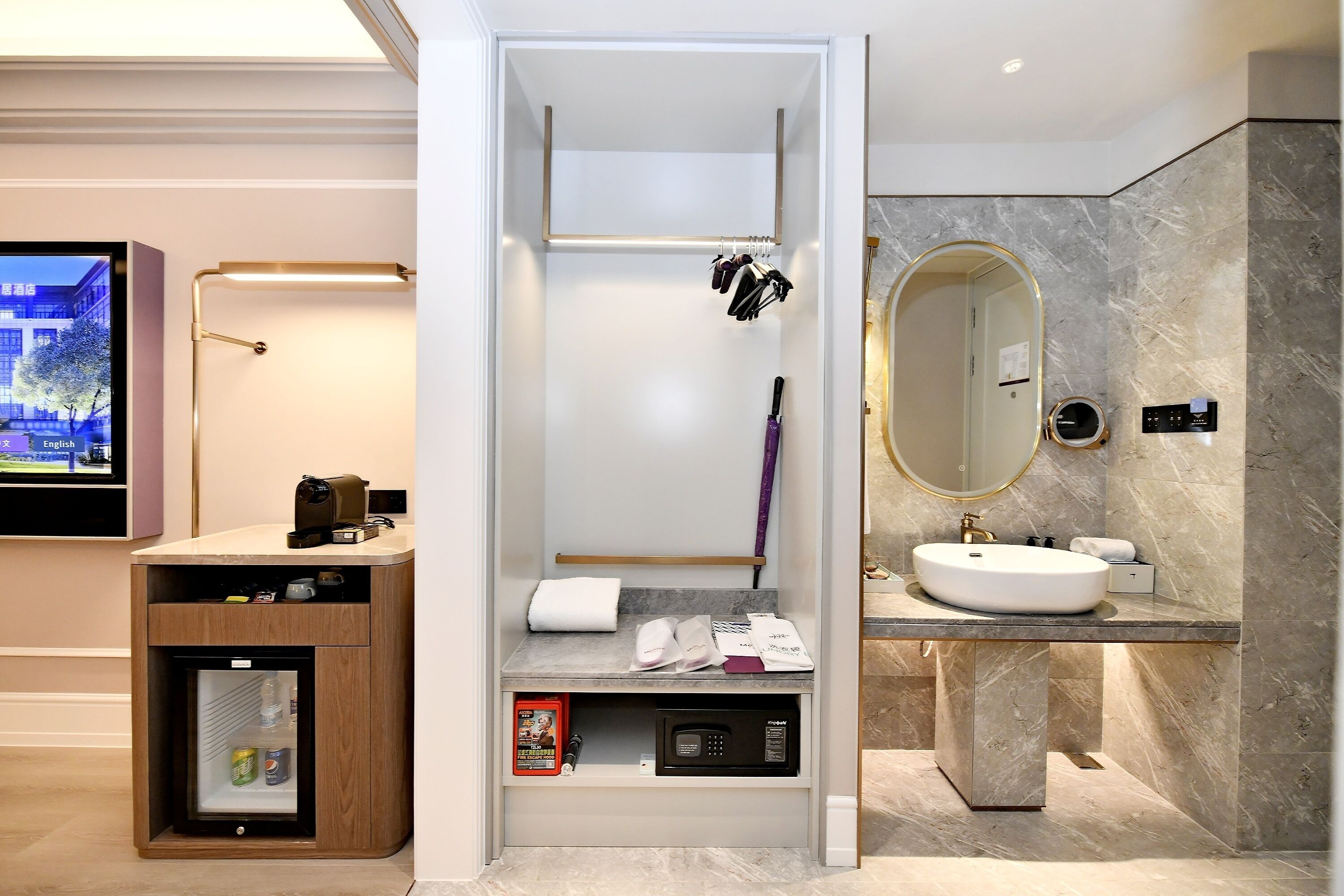 A modern bathroom with a vanity, a shower area, a built-in refrigerator, and a television.