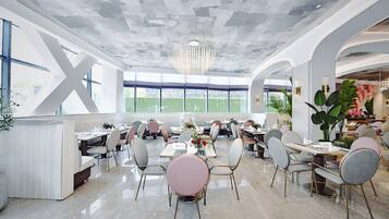 Een ruime eethoek met modern meubilair, grote ramen en een uniek plafondontwerp.