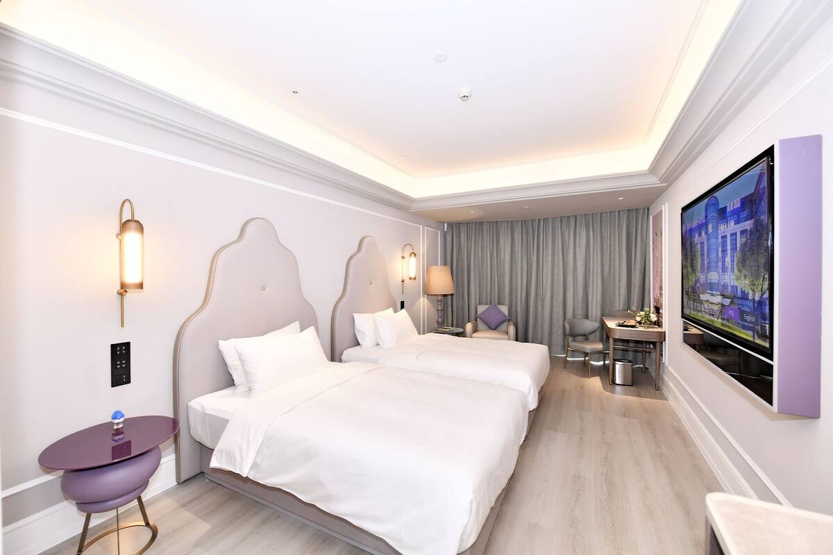Ein Hotelzimmer mit Doppelbett, Schreibtisch mit Stuhl, Fernseher und kleinem Tisch.