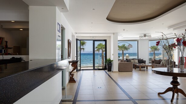A spacious lobby with a view of the ocean, a reception desk, and a seating area with a round table.
