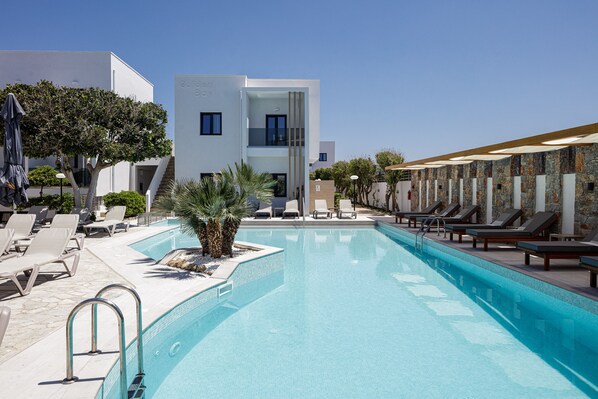 A modern hotel with a swimming pool, lounge chairs, and a clear blue sky. - Golden Bay Boutique Hotel & Bungalows (Hersonissos)