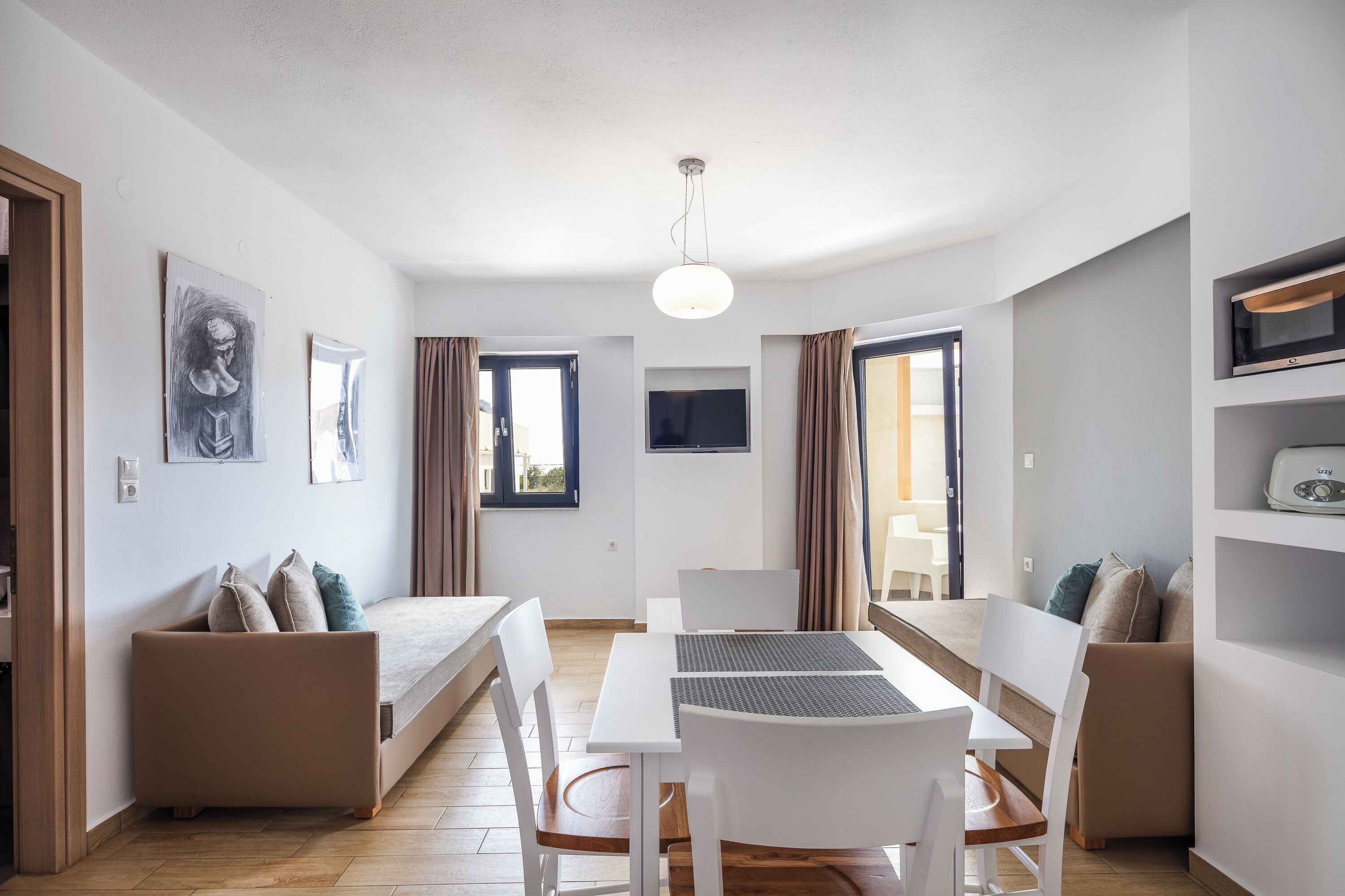Una habitación moderna y bien iluminada con una mesa de comedor, sillas, un sofá y una televisión.
