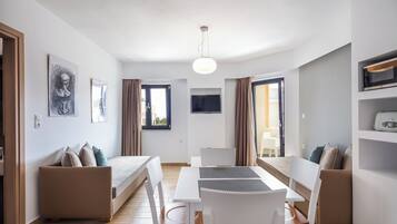 Una habitación moderna y bien iluminada con una mesa de comedor, sillas, un sofá y una televisión.