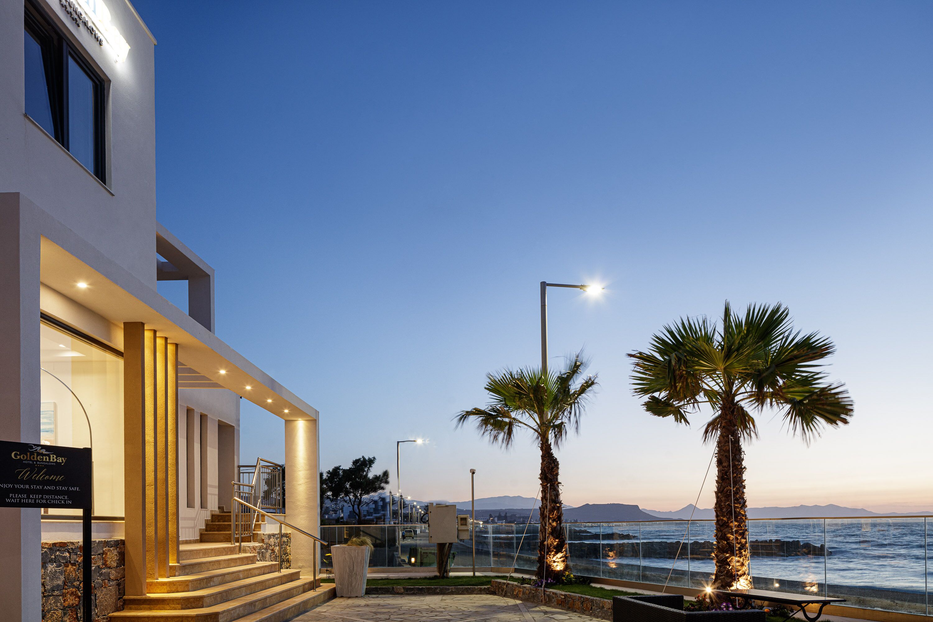 Un hotel moderno con una entrada acogedora, una escalera que conduce a los pisos superiores y vistas al mar.