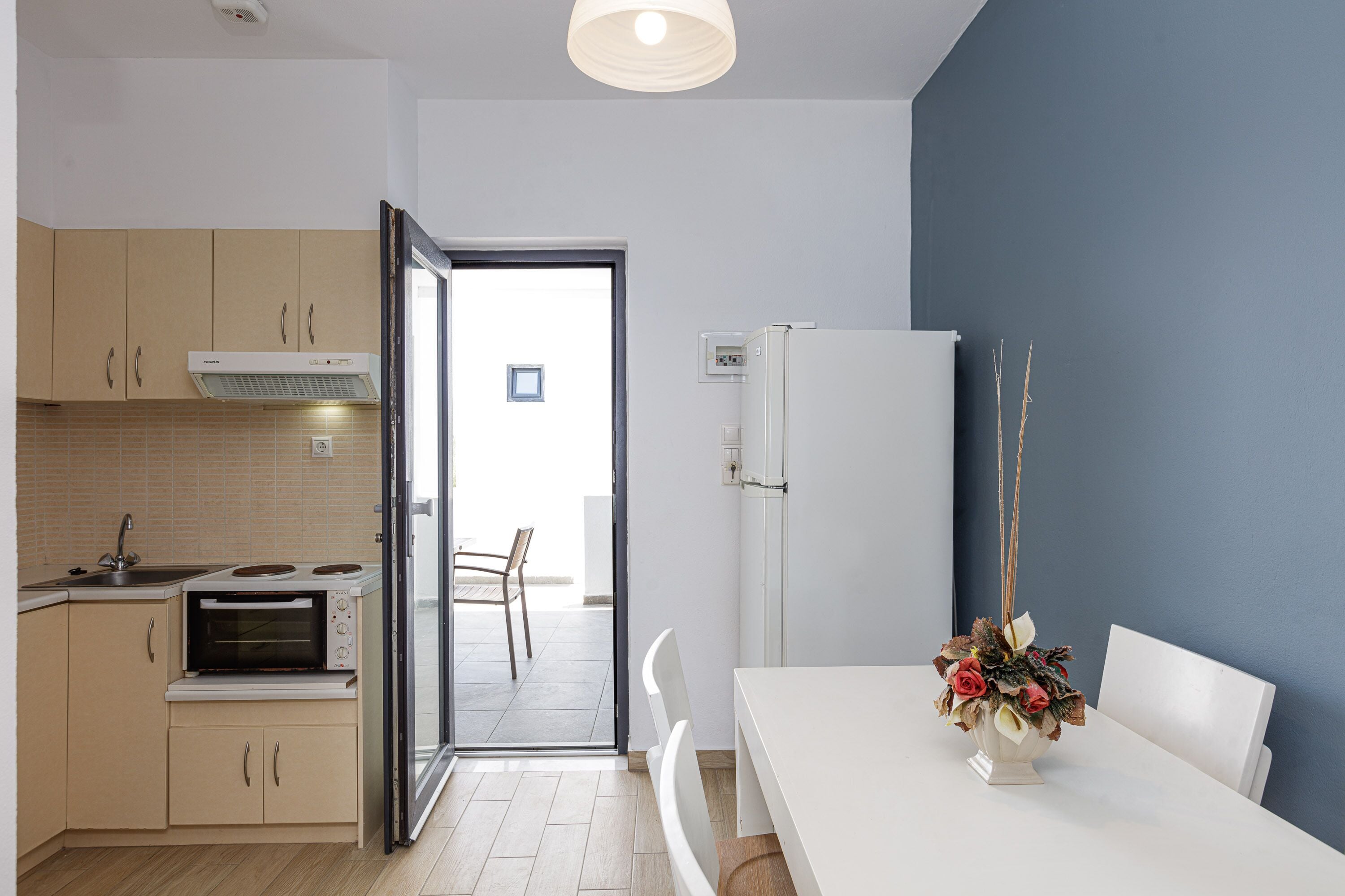 Een moderne keuken met een ingebouwde oven, een koelkast en een eethoek met een witte tafel en stoelen.