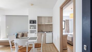 A compact living space with a dining area, kitchenette, and a bedroom.