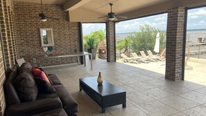 A spacious living area with a brick wall, a black sofa, a coffee table, and a view of the outdoors. - Lakefront Property -Small Gatherings  (Houston)