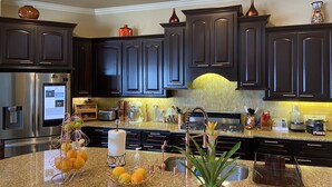 A modern kitchen with dark cabinetry, stainless steel appliances, and a granite countertop. - Lakefront Property -Small Gatherings  (Houston)