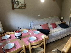 Ein Essbereich mit Tisch für zwei Personen, einer Couch mit Kissen und einer Wandleuchte.