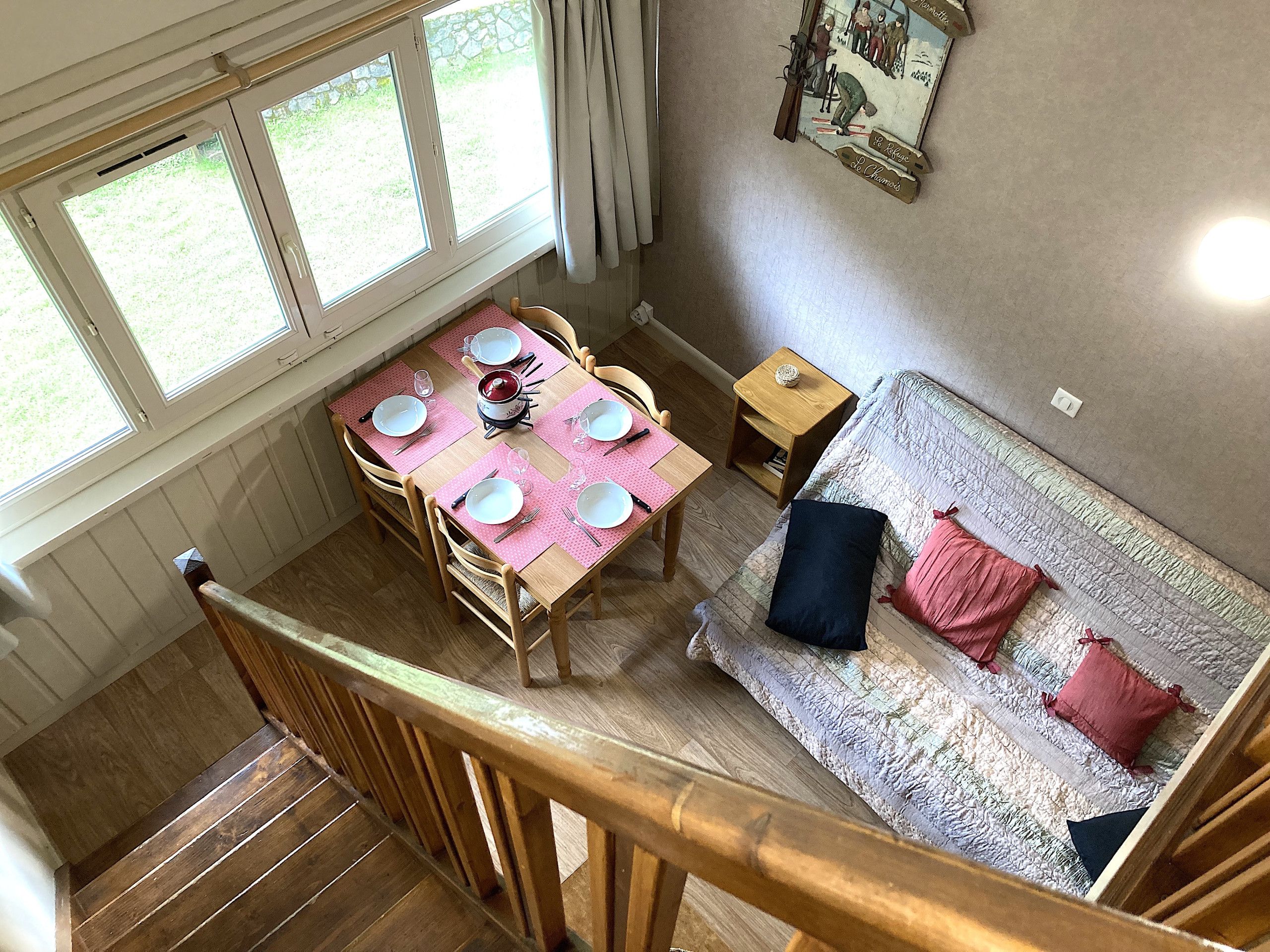 A dining area with a table set for four, a sofa with cushions, and a small wooden side table.