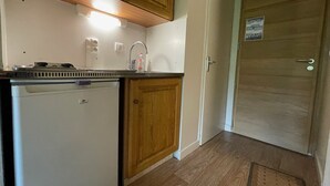Una cocina compacta con armarios de madera, lavavajillas integrado y un lavabo.