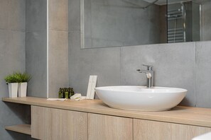 Une salle de bain moderne avec un grand lavabo sur pied blanc, un plan de toilette en bois et un miroir au-dessus.