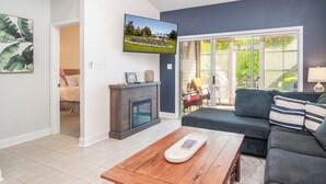 A living room with a fireplace, a television mounted on the wall, a sofa, and a coffee table. - TB 94B Dog friendly Garden home in the peaceful True Blue community. (Pawleys island)