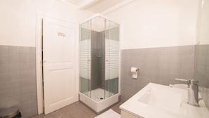 A bathroom with a glass-enclosed shower, a white sink, and grey tiled walls. - 🎖 Le Parmelan - apartment for 2 people in the heart of the old town (Annecy)