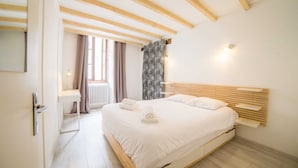 A bedroom with a wooden bed frame, white bedding, a bedside table, and a window with curtains. - 🎖 Le Parmelan - apartment for 2 people in the heart of the old town (Annecy)