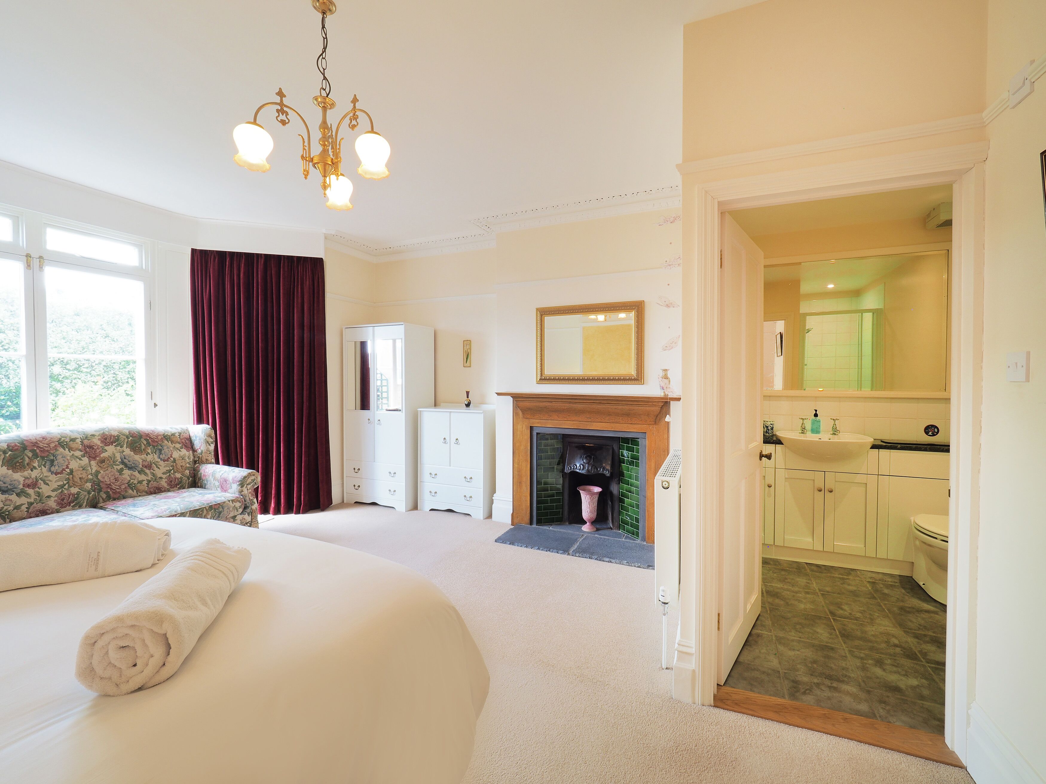 A bedroom with a bed, a dresser, a mirror, and a fireplace.
