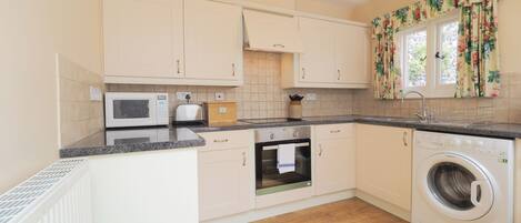 A compact kitchen with a microwave, toaster, oven, and washing machine.