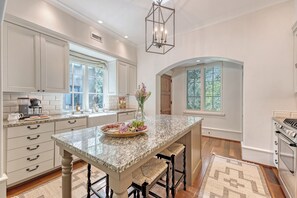 A kitchen with white cabinetry, a marble island, and a built-in oven. - New to Rental Market!  Stunning home in perfect, central location (Kiawah Island)