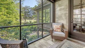 Un balcon agrémenté de meubles en osier, une porte avec des panneaux de verre et une vue sur la verdure.