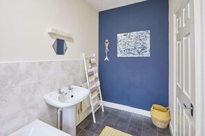 A bathroom with a white sink, a towel rack, a blue accent wall, and a yellow woven basket. - Host & Stay | Ocean Breeze (Scarborough)