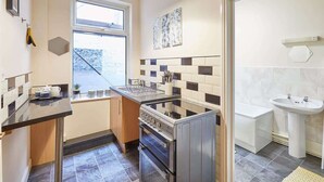 A compact kitchen with a stove, oven, and a window. - Host & Stay | Ocean Breeze (Scarborough)