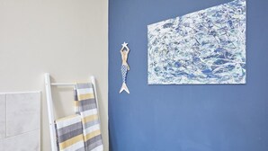 A bathroom with a towel rack holding a striped towel, a wall-mounted star decoration, and a blue abstract painting. - Host & Stay | Ocean Breeze (Scarborough)