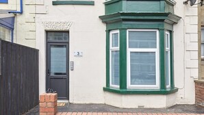 A corner bay window with green trim, a dark door, and a brick step leading to the entrance. - Host & Stay | Rockpool (Scarborough)