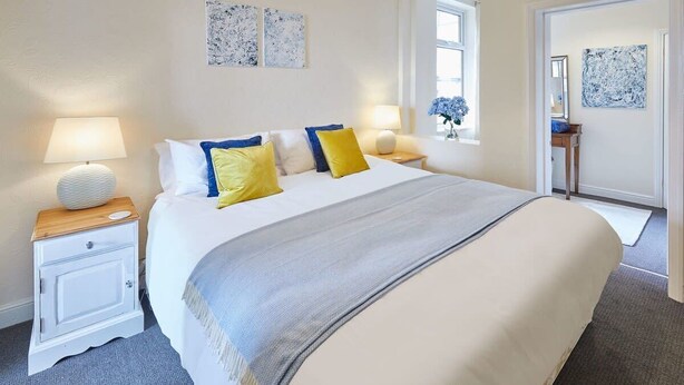 A neatly arranged bedroom with a large bed, bedside lamps, and artwork on the walls. - Host & Stay | Rockpool (Scarborough)