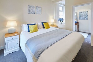 A neatly arranged bedroom with a large bed, bedside lamps, and artwork on the walls. - Host & Stay | Rockpool (Scarborough)