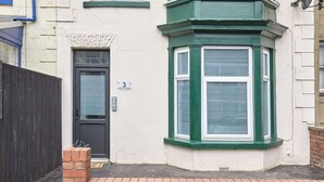 A corner bay window with green trim, a black door, and a number '3' sign.