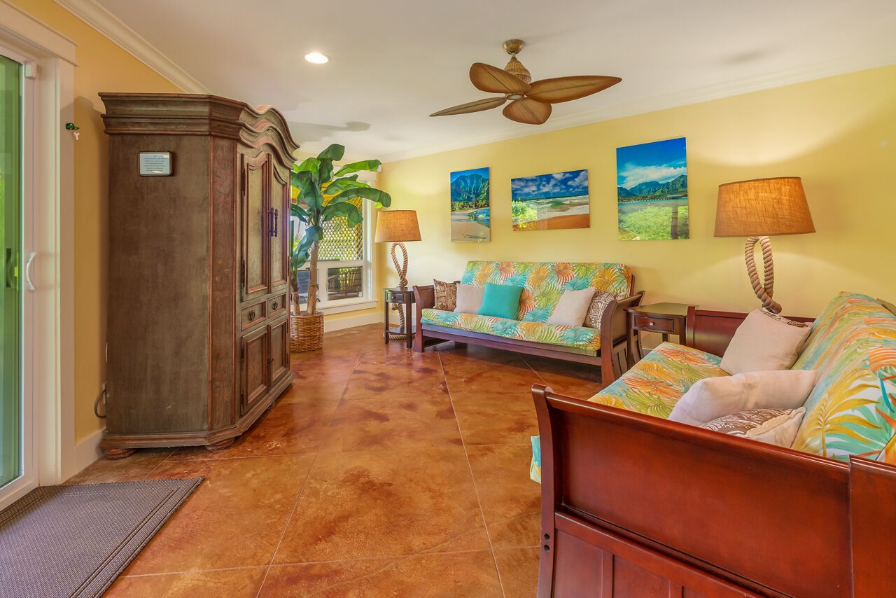 A living room with a sofa, a cabinet, and a ceiling fan.