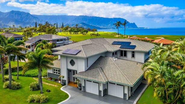 A large, modern house with a spacious driveway, solar panels, and a well-maintained lawn. - Hawaii Life Rentals Presents Hale Ohana Nui (Princeville)