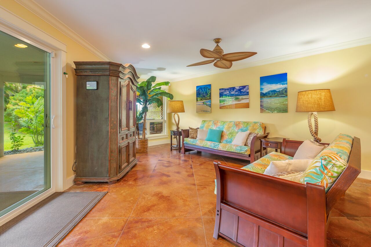 A spacious living area with a sofa, a wooden cabinet, and a ceiling fan.