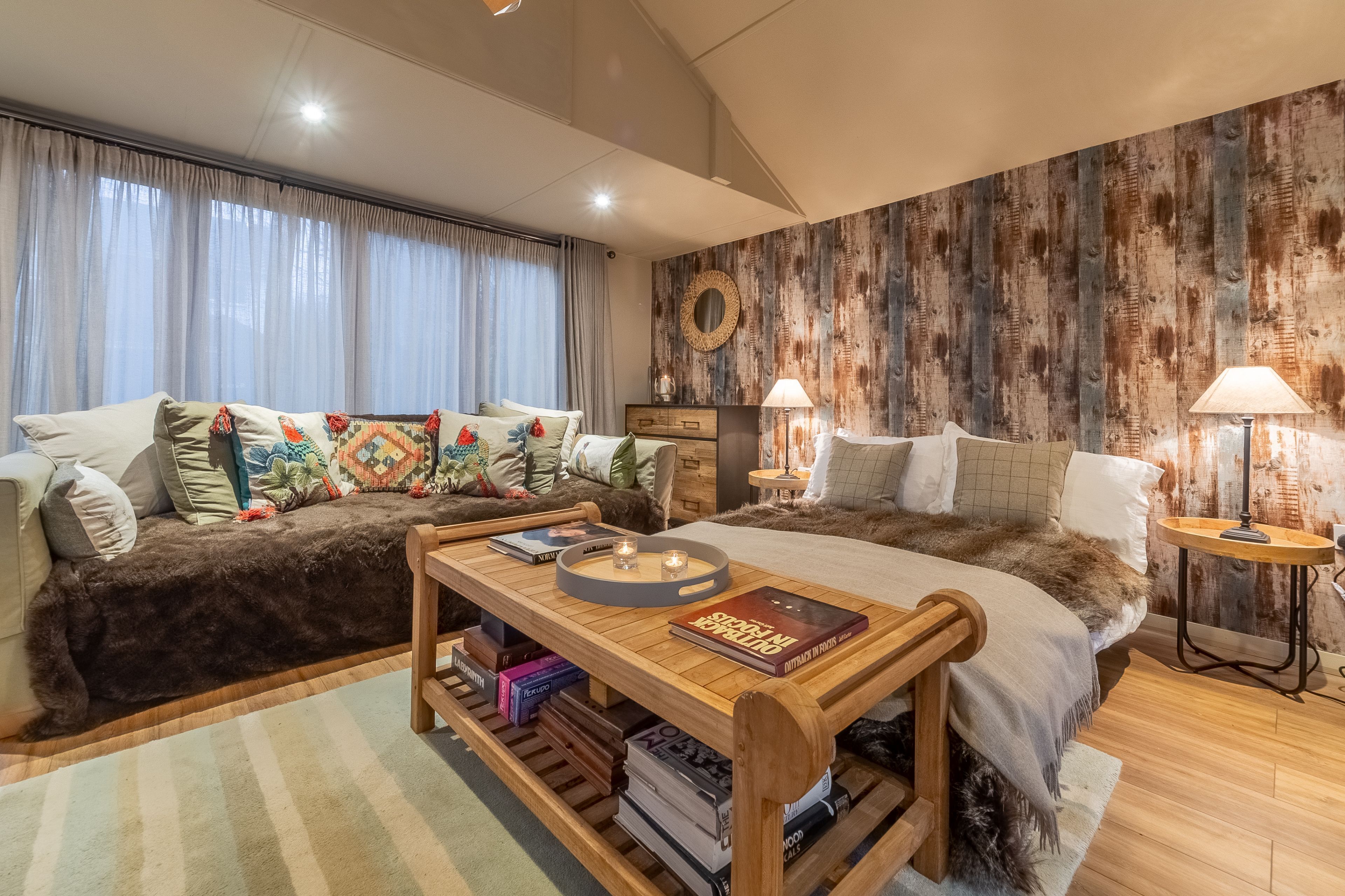 Un dormitorio acogedor con cama, sofá, una mesa de centro de madera con libros y una pared rústica.
