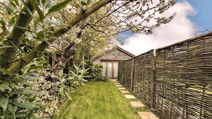 A garden pathway leading to a house with a wooden fence and a small shed. - The Bothy, Ringstead, Norfolk (Ringstead)