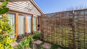 A wooden house with a garden and a bamboo fence. - The Bothy, Ringstead, Norfolk (Ringstead)