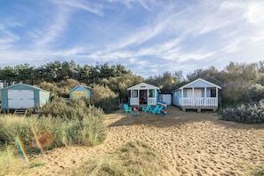 A beachside property with three cabins, each with a porch and seating area. - The Bothy, Ringstead, Norfolk (Ringstead)