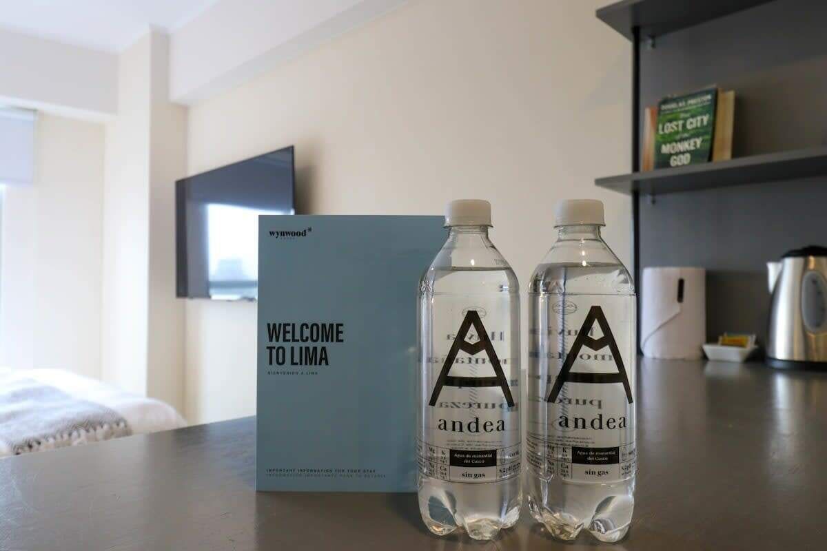 Dos botellas de agua con la etiqueta 'andea' y un cartel que dice 'BIENVENIDOS A LIMA' sobre una mesa.