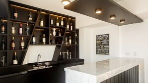A bar area with shelves of liquor bottles, a marble countertop, and a wall sign listing various spirits. - w* | Amazing Loft in Barranco (Barranco)