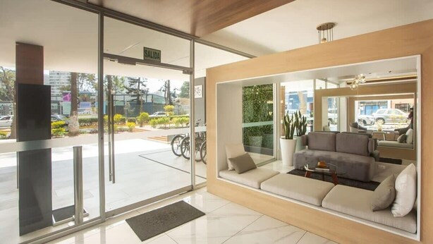 A modern hotel lobby with a glass entrance, a seating area with a sofa and coffee table, and a view of the street outside. - w* | Amazing Loft in Barranco (Barranco)