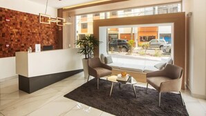 A modern reception area with a wooden wall, a reception desk, two armchairs, a coffee table, and a large window offering a view of the street. - w* | Amazing Loft in Barranco (Barranco)