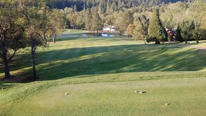En golfbane med et klubhus, omgivet af træer og bakker.